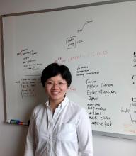 Woman smiling in front of white board with writing on it