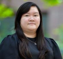 woman with long dark hair and a black blouse on smiling lightly
