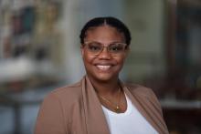 woman with her hair tied back and clear glasses on smiling