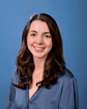 a woman in a silk blue top with long brown hair smiling