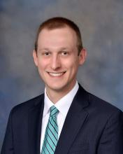 man in a suit with a striped blue tie on smiling