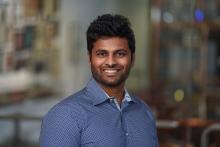 man in a blue shirt with dark brown hair smiling