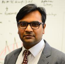 man with dark hair and glasses on smiling