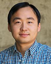 man with dark, side-parted hair smiling