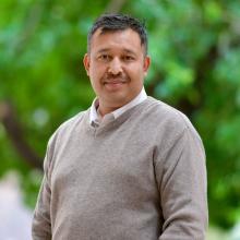 man in a light brown sweater smiling