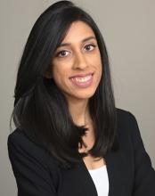 woman with dark hair in a black blazer smiling