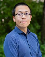 man in a blue button down shirt smiling lightly