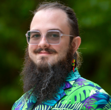 man with a longer beard and bright suit on smiling