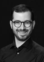 man with dark, circle glasses smiling