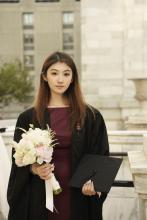 woman in a graduation gown holding flowers