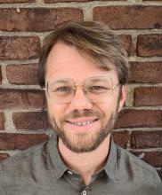 man with brown hair and glasses on smiling