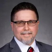 man with dark hair and glasses on smiling