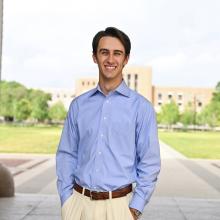 main in a blue button down smiling