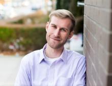 man in a pastel button down smiling