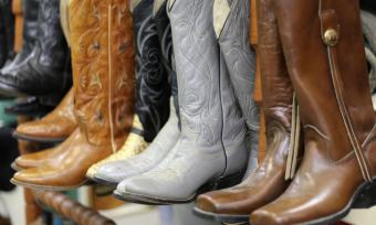 Photograph of brown and grey cowboy boots lined up on display shelf.
