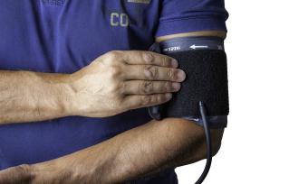 Photo of a man's arm wearing a blood pressure cuff. 