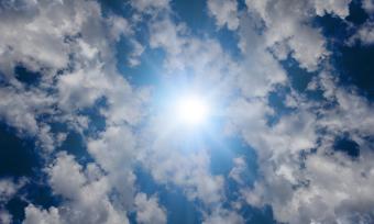 Photo of the sky showing the sun and clouds