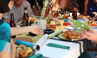 Photo of a dining table with plates / food and Christmas favors, showing friends gathered to party. 