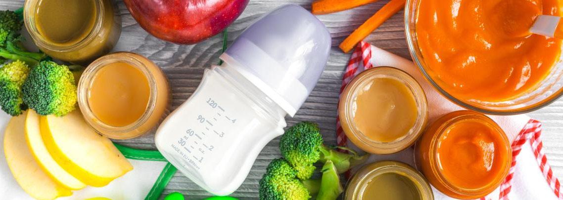 photo of baby bottle surrounded by fruits and vegetables