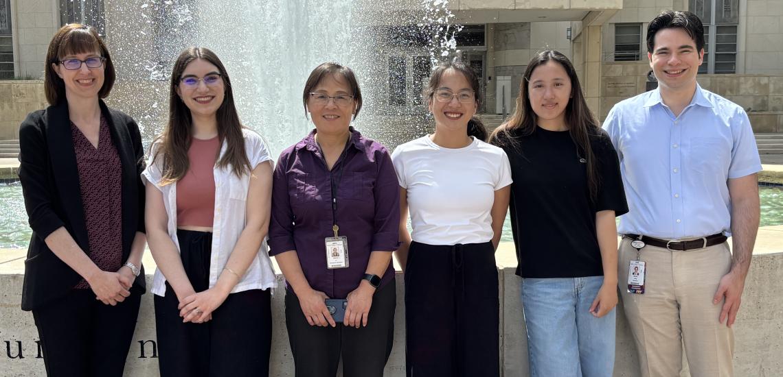 group of 6 people standing in front of a fountain. 
