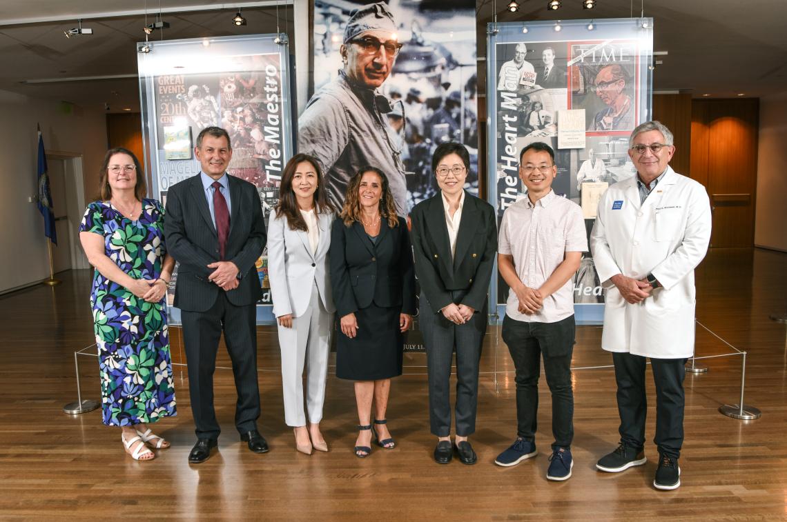 Group of people standing in front of a large photo of a doctor