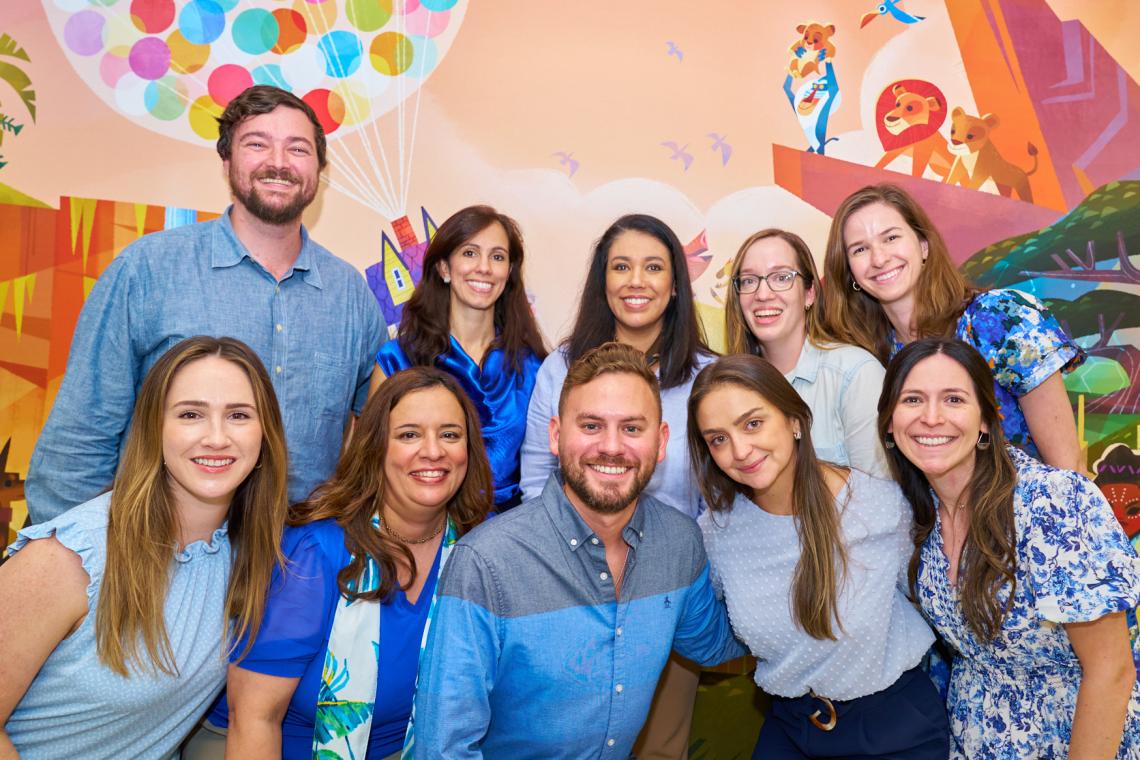 group of people standing in front of a children's mural, smiling