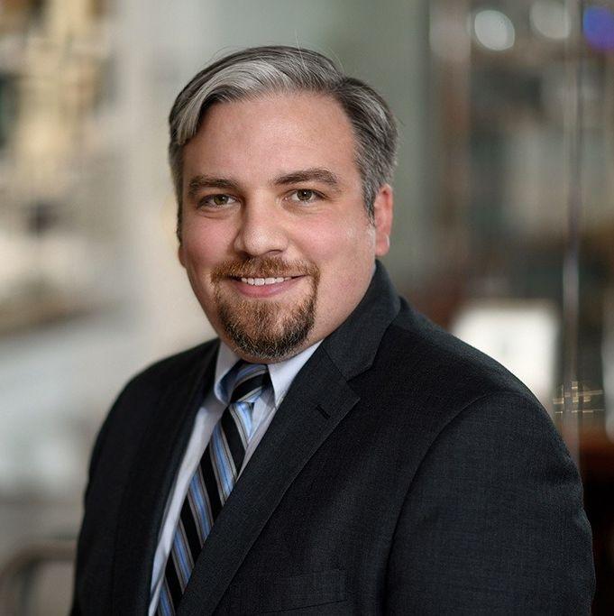 man in dark grey suit smiling
