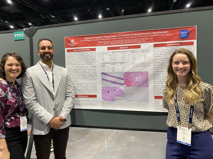 3 people standing by scientific poster and smiling