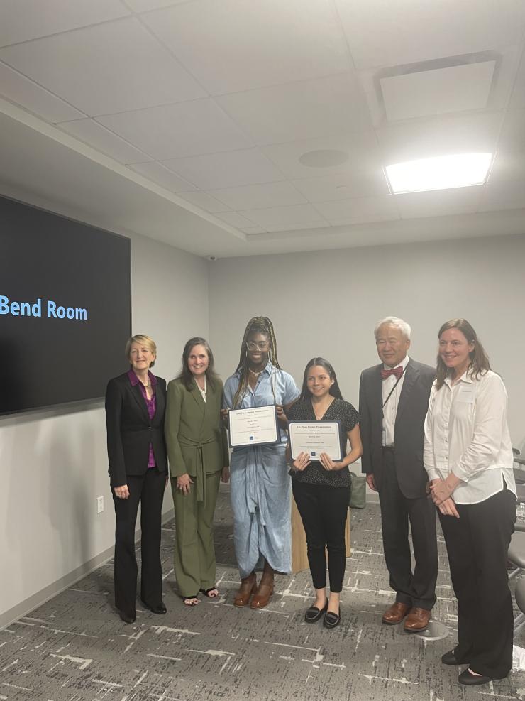 award winners holding certificates and smiling with a group of people