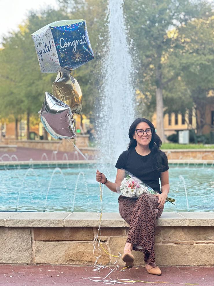 woman sitting in front of a fountain, holding a balloon