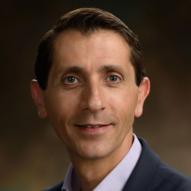 photo of man smiling in front of brown background