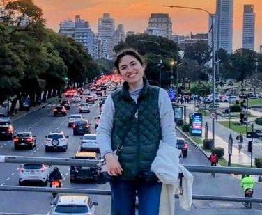 Woman smiling on a bridge overlooking traffic in a city