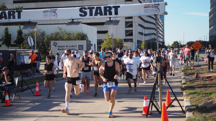 A pack of runners crossing a finish line during a race on a sunny day
