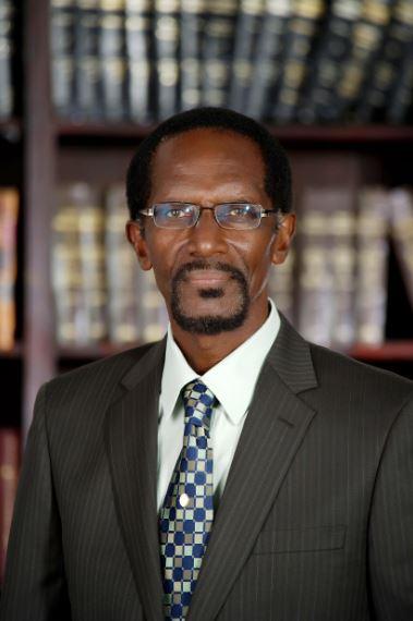 man with glasses on in a suit smiling lightly