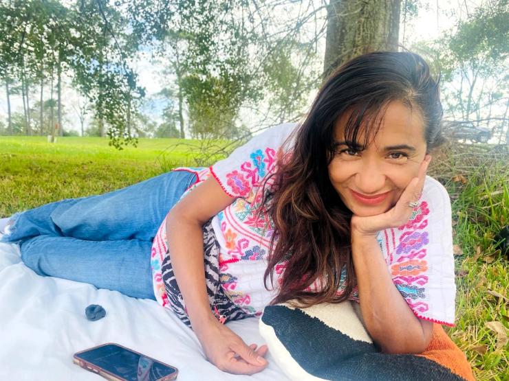 woman smiling outside while laying on her side