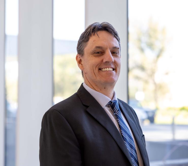 a man in a suit with a blue tie on smiling