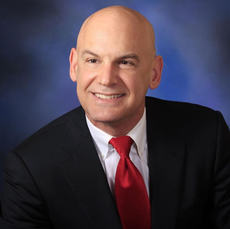 man ina black suit with a red tie on smiling