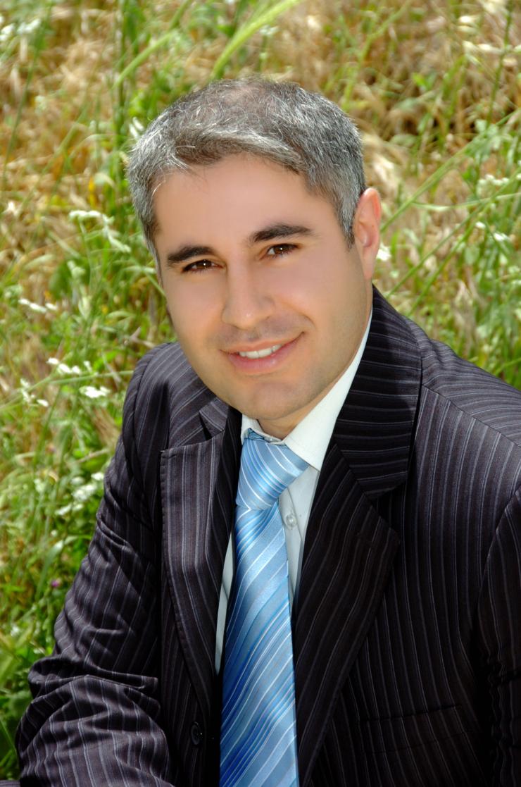 man in a suit, sitting in grass smiling