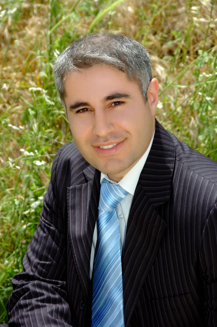 man in a suit, sitting in grass smiling