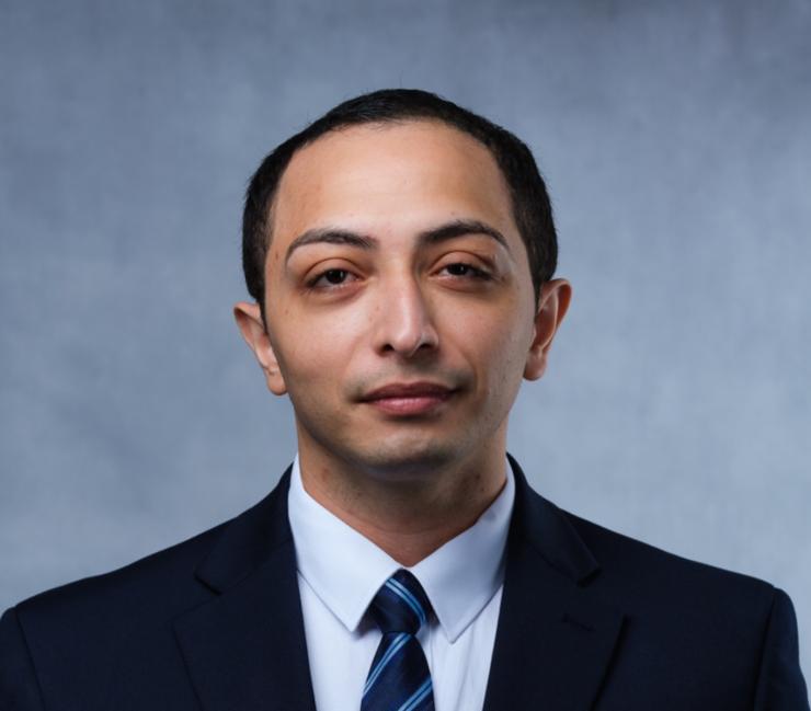 man in a suit with short dark hair smiling lightly