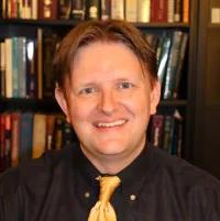 man smiling in front of a bookcase