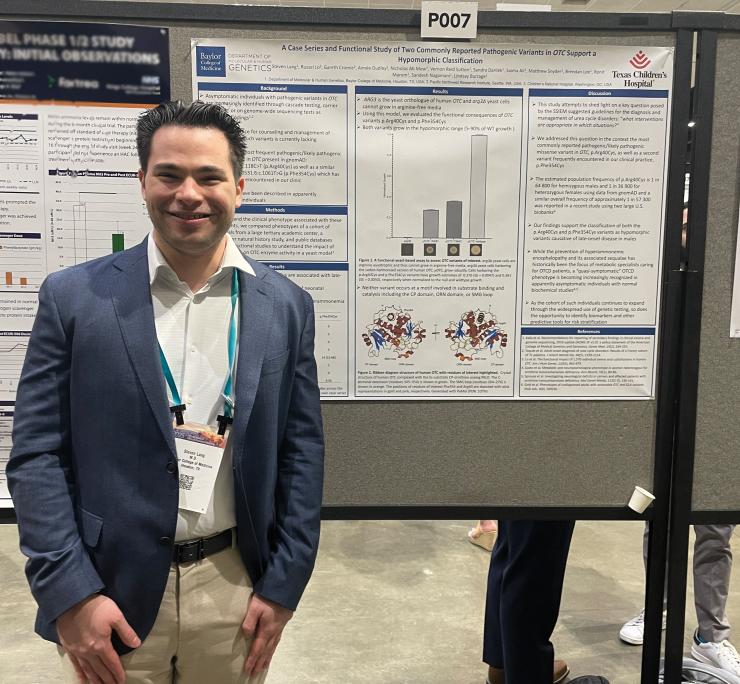 man smiling in front of a poster