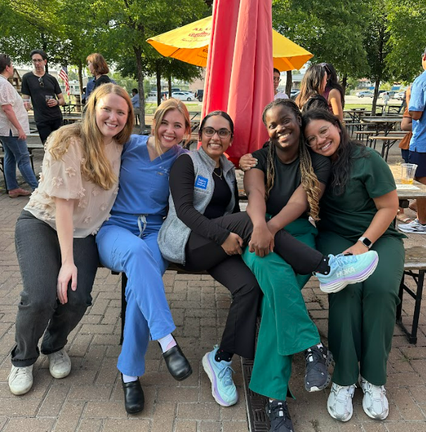 Smiling students outdoors under an umbrella