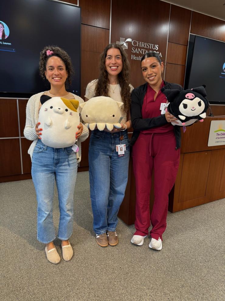 3 women holding stuffed animals and smiling