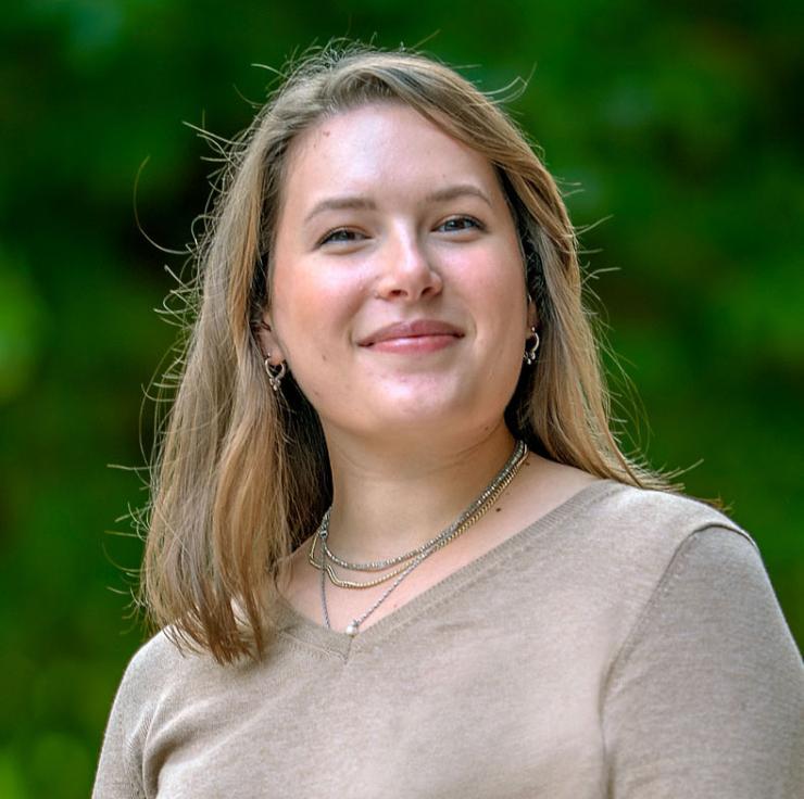 Woman smiling in while outside in front of trees