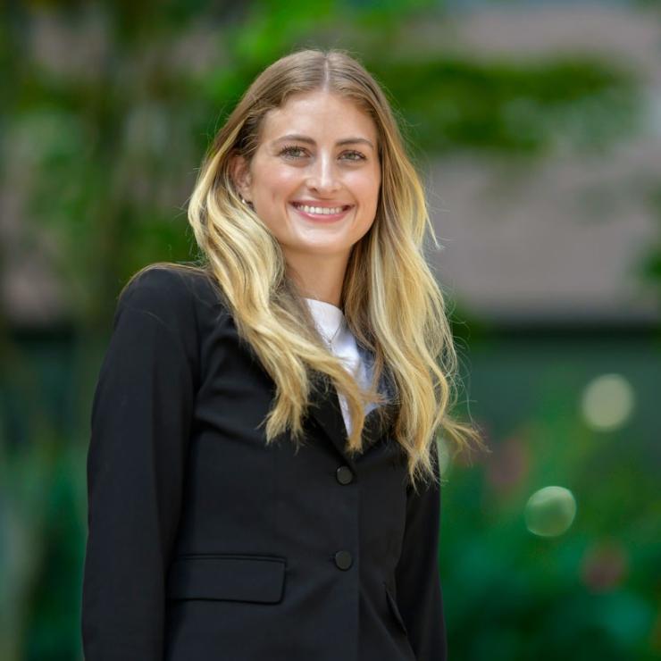 Woman smiling outside in front of trees