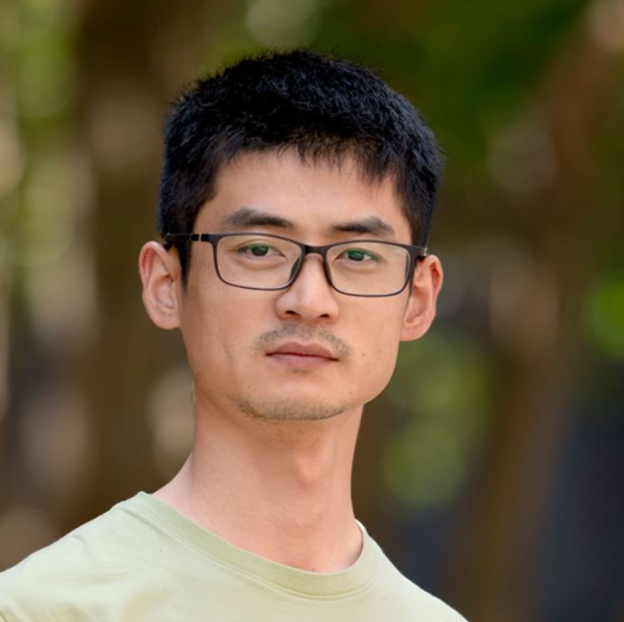 man smiling outside in front of trees