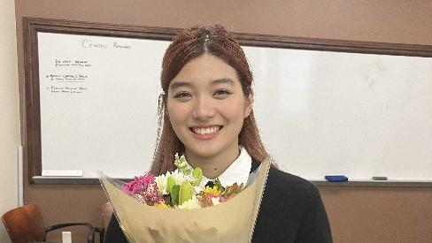woman holding flowers in front of a white board.
