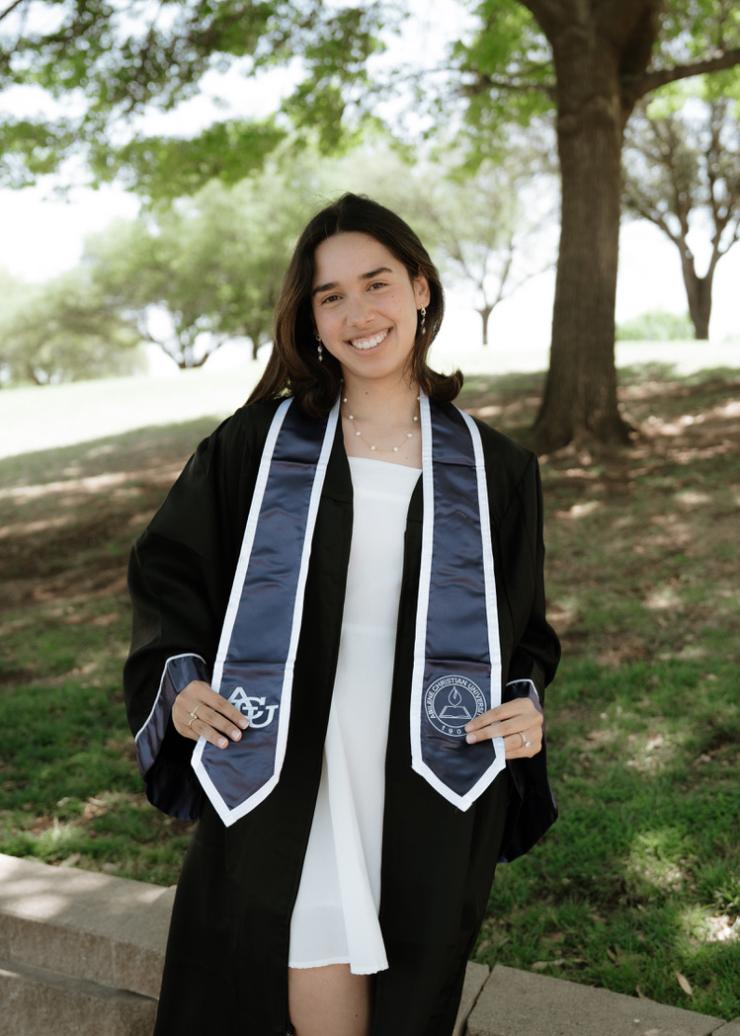 woman with dark hair in a graduation gown smiling