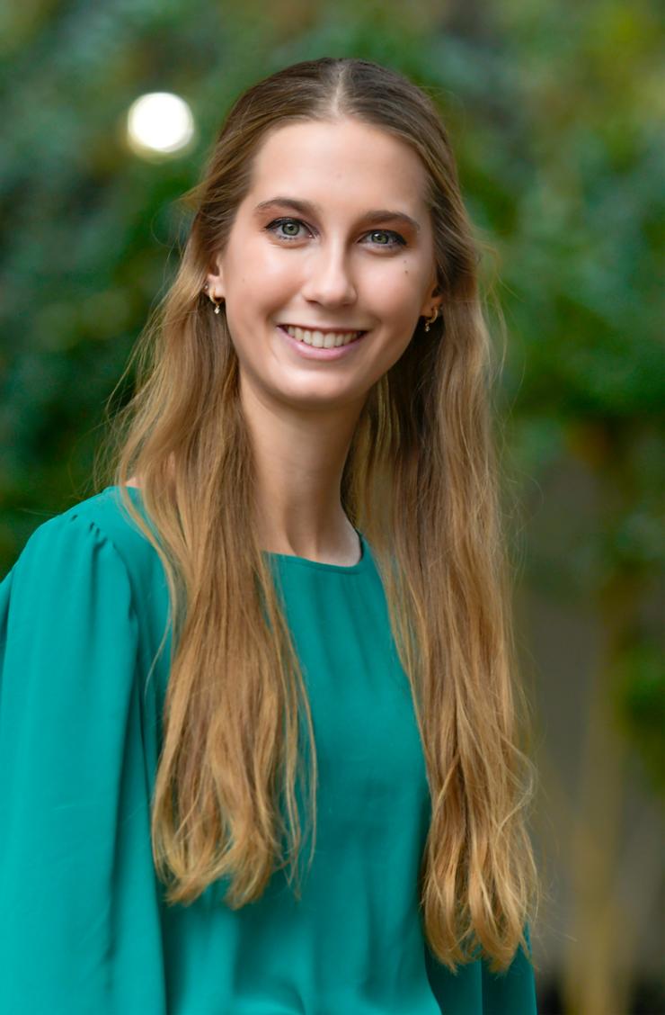 woman with long blonde hair in a teal blouse, smiling